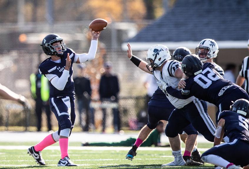 保利预科 大学运动代表队 足球 Quarterback throwing the ball as defense holds off the other team